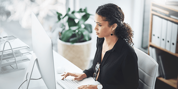 A woman is working on her desktop computer in a neat modern office.